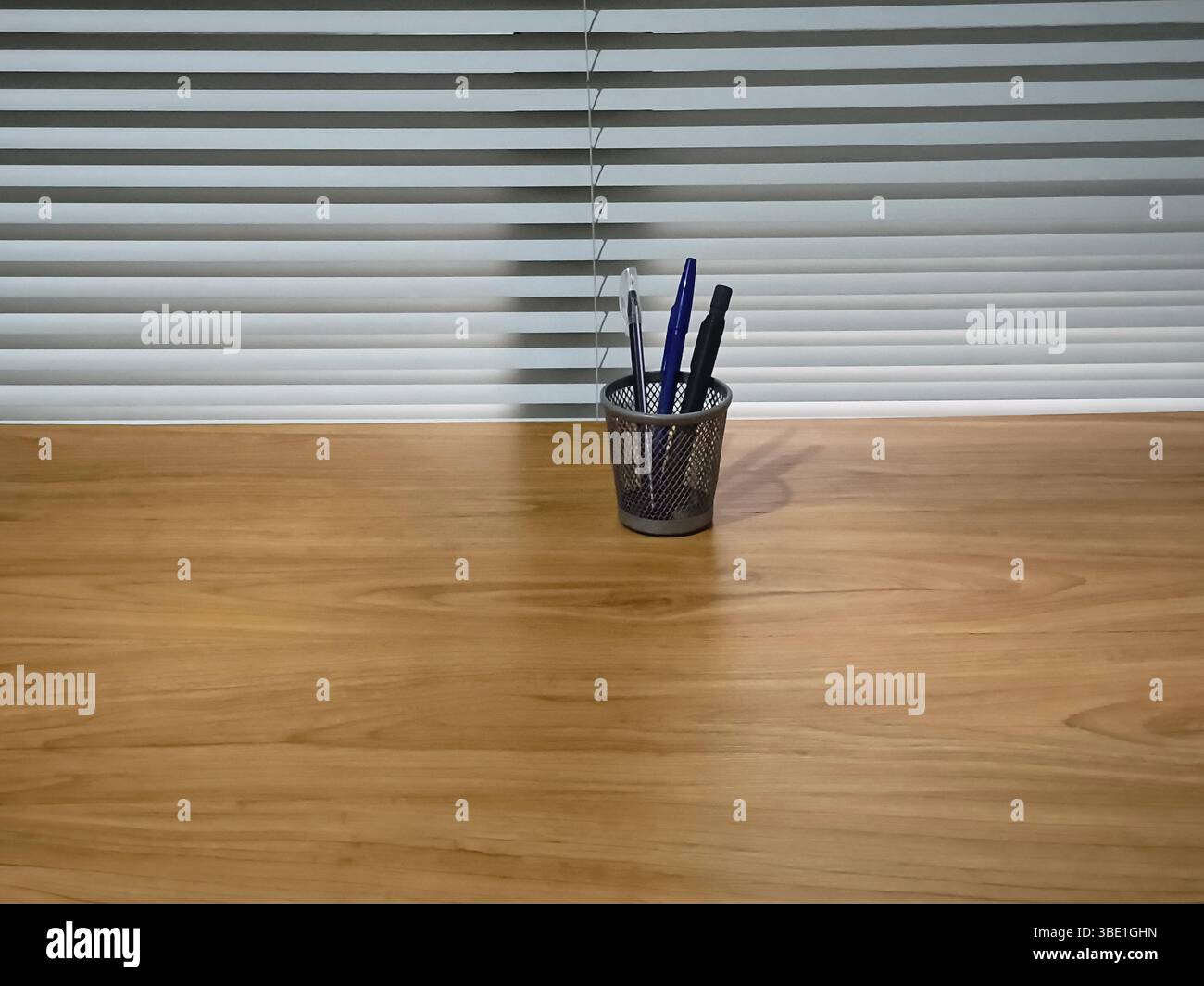 crayons et stylos dans un récipient sur une table en bois Banque D'Images