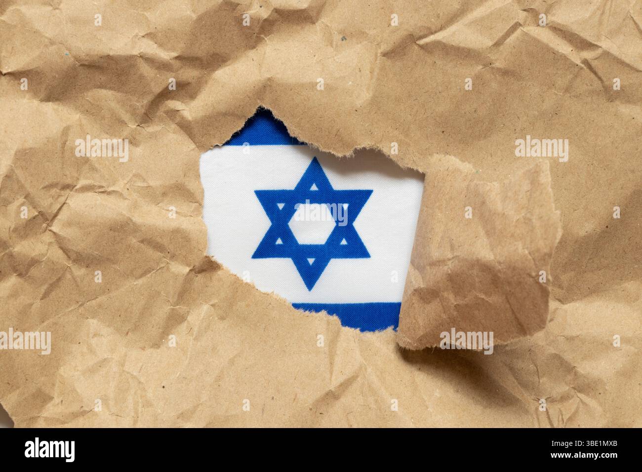 Drapeau d'Israël vu à travers du papier kraft déchiré comme symbole, identité, statut d'État Banque D'Images