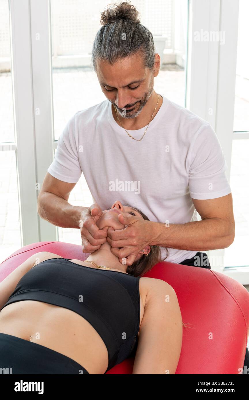 Ostéopathe massant le muscle digastrique d'un patient au cours d'une séance de physiothérapie en clinique médicale Banque D'Images