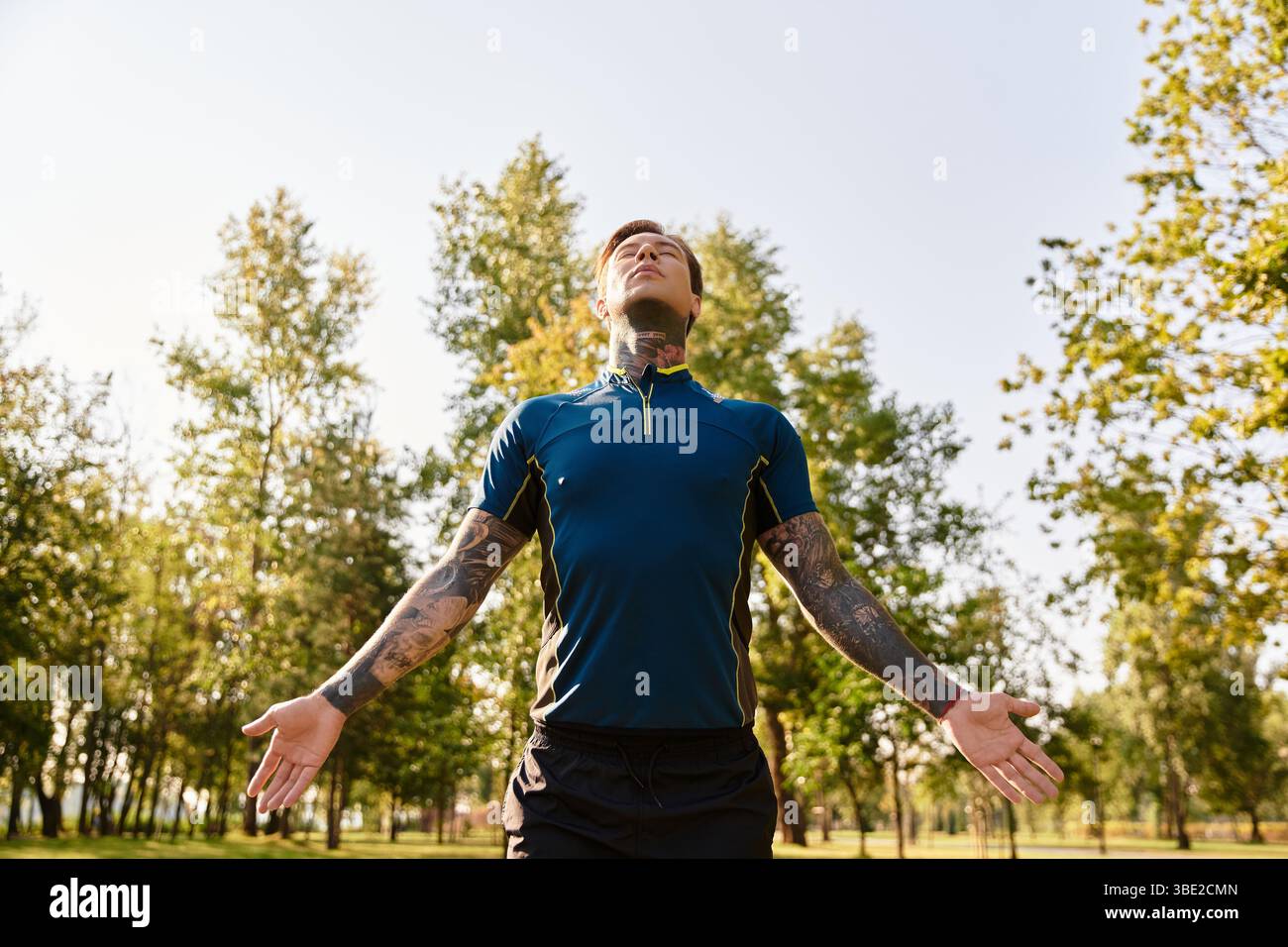 Un jeune homme prend une promenade rafraîchissante dans un parc serein entouré de verdure luxuriante. Banque D'Images