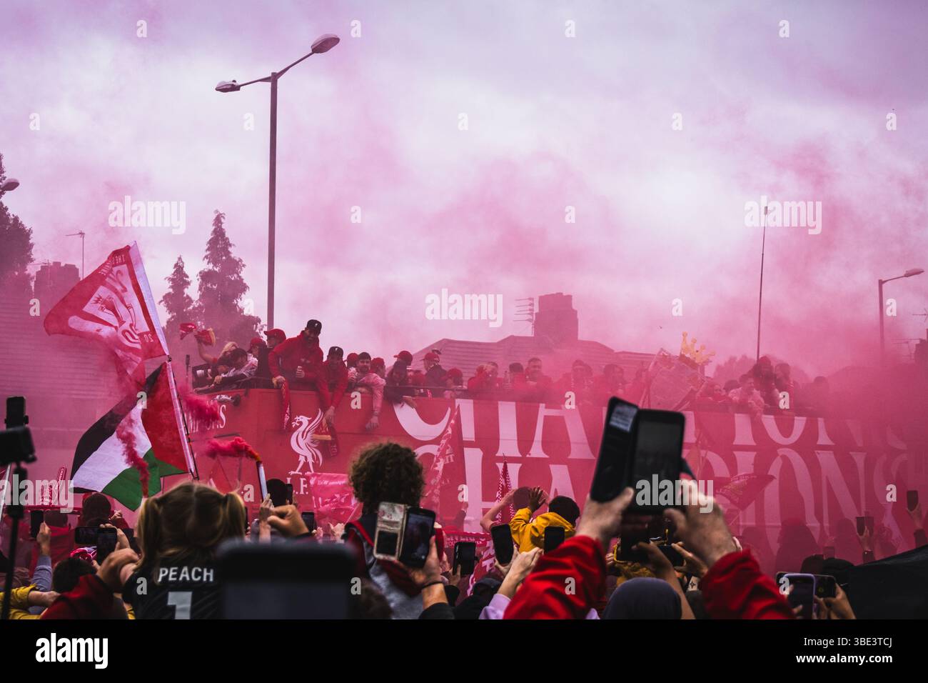 Des foules de fans de Liverpool avec des bombes fumigènes rouges et des drapeaux sur Queens Drive pour accueillir le bus du Liverpool FC pendant la parade des trophées de la premier League. Banque D'Images