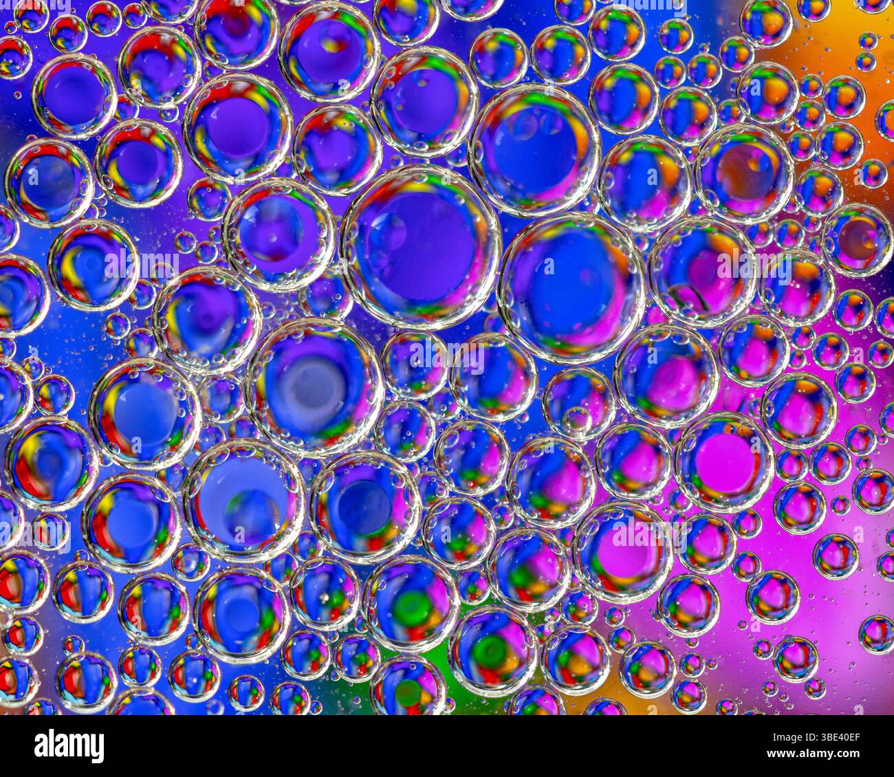 Bulles d'huile flottant sur l'eau avec un fond astract coloré Banque D'Images