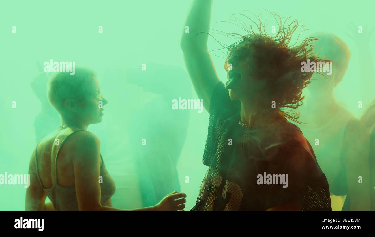 Des gens silhouettés dansant dans une ambiance de fête vibrante et colorée. Banque D'Images