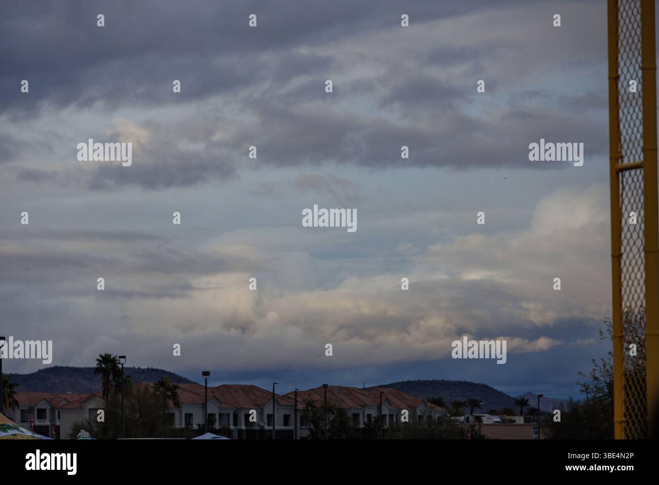 Ciel Moody avec des nuages spectaculaires sur les toits de banlieue et les montagnes désertiques lointaines, capturant une journée orageuse dans le sud-ouest américain. Banque D'Images