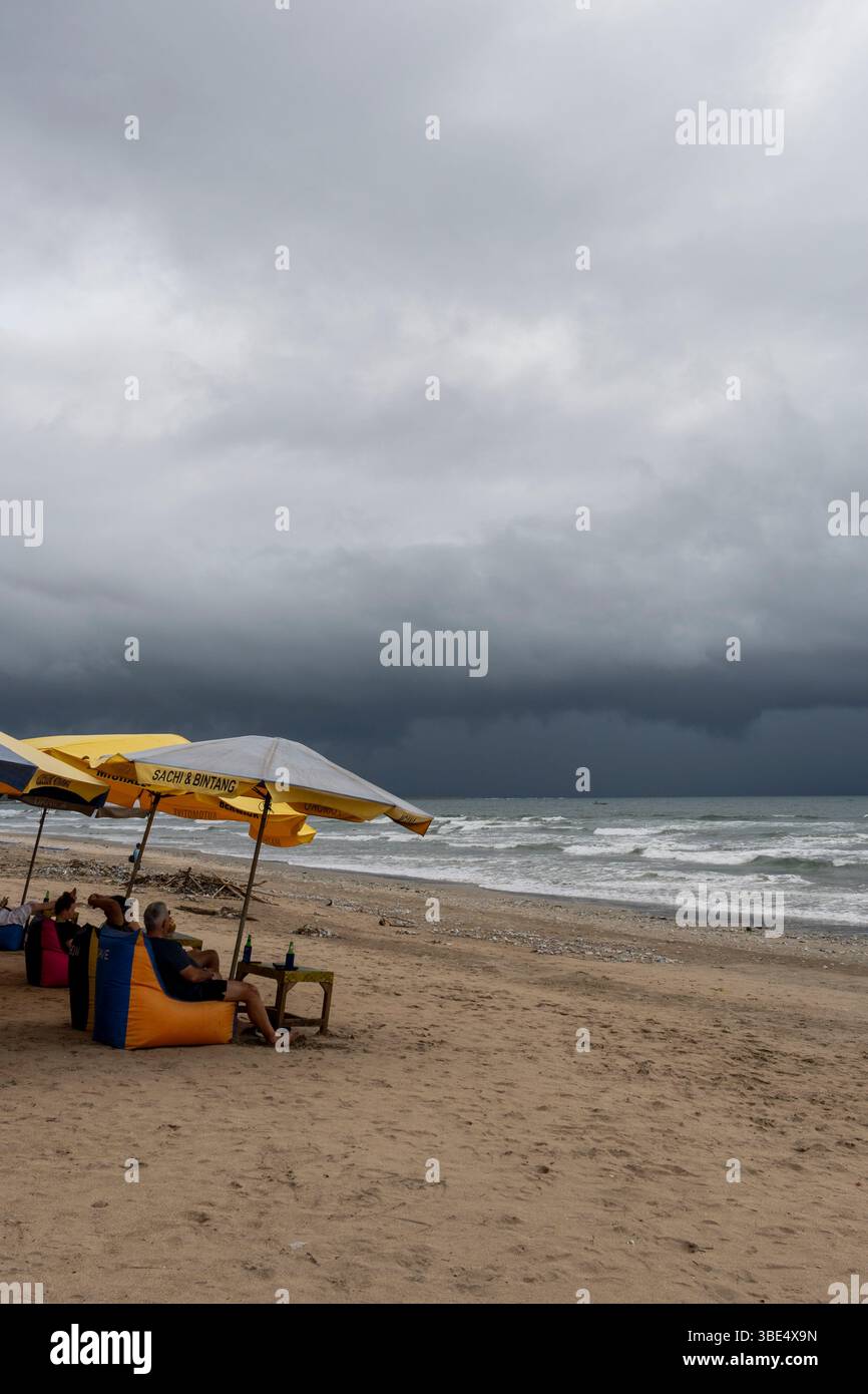 Bali, Indonésie-Dec28,2024 : scène de plage avec chaises de plage colorées et parasols. Les chaises sont disposées en rangée et il y a plusieurs tables dans le Banque D'Images