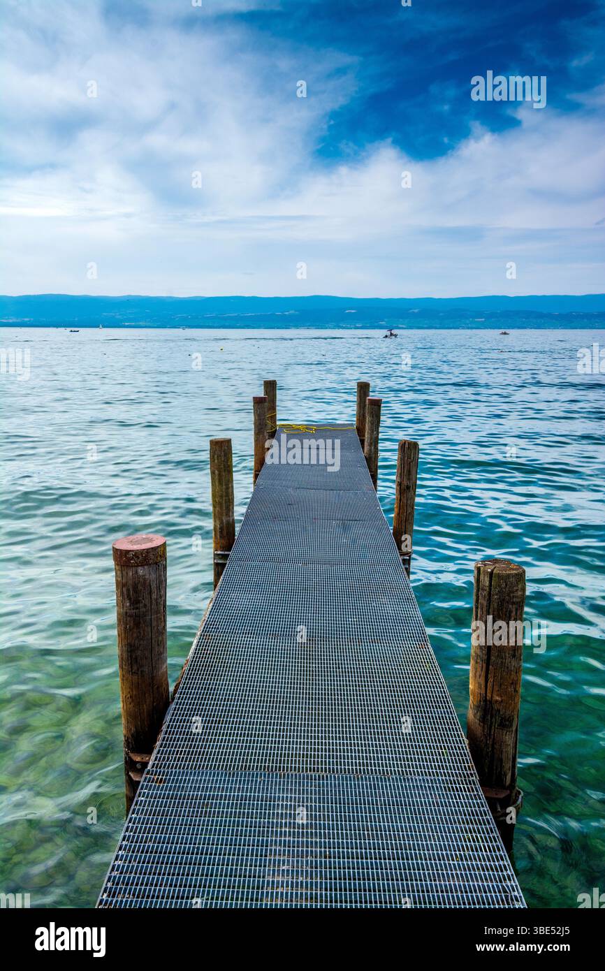 Une jetée robuste s'étend dans les eaux sereines du lac Léman, entouré de teintes bleues envoûtantes et d'une atmosphère tranquille. Haute Savoie. France Banque D'Images