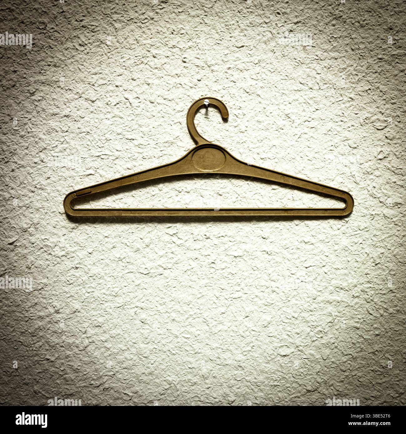 Un cintre est suspendu à un mur texturé, mettant en valeur un design minimaliste. Le réglage intérieur simple permet à la mise au point de rester sur le cintre Banque D'Images