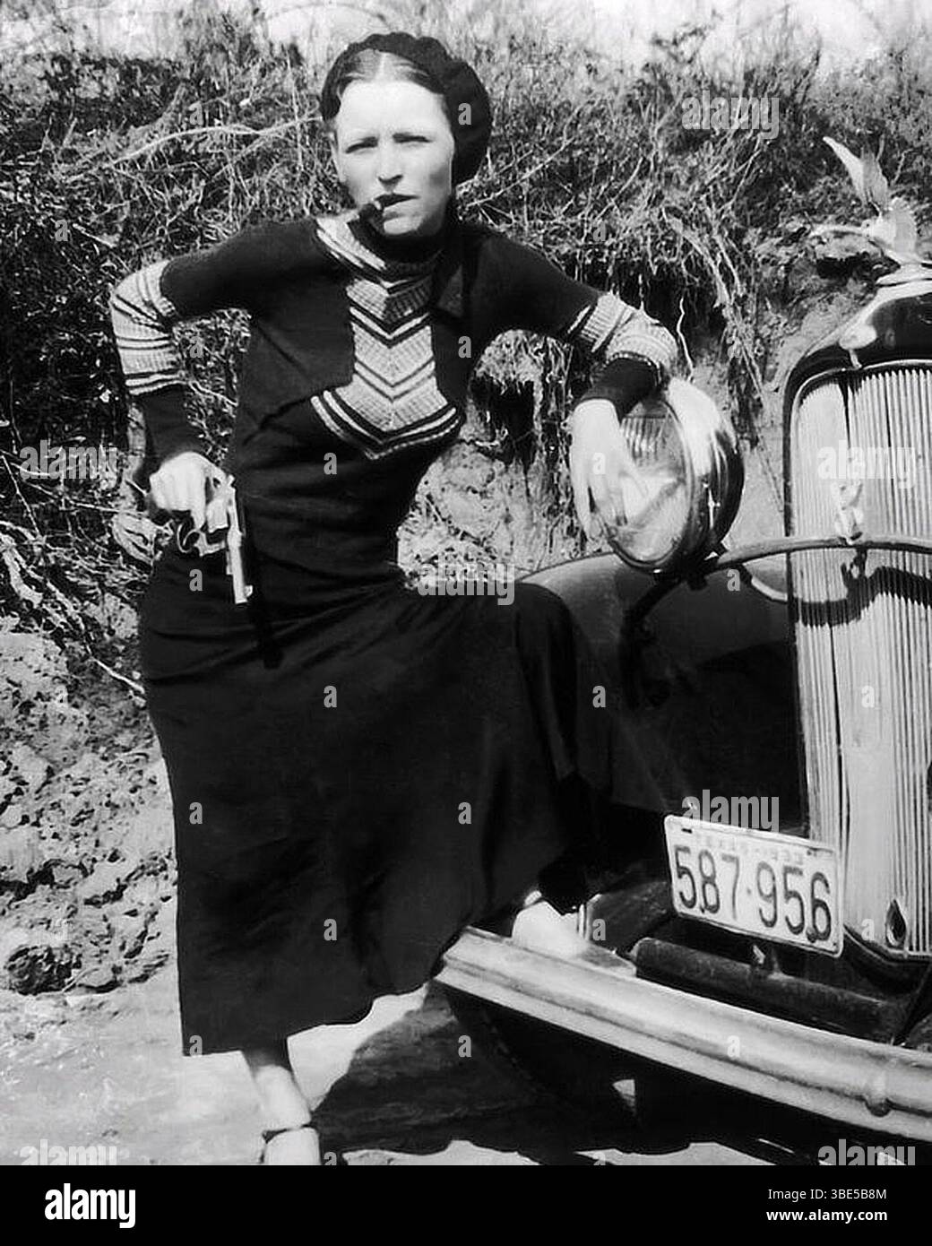 Bonnie Prker pose avec un cigare et un pistolet. Bonnie Elizabeth Parker (1er octobre 1910 – 23 mai 1934) et Clyde Chestnut 'Champion' Barrow (24 mars 1909 – 23 mai 1934) étaient des hors-la-loi américains qui ont voyagé dans le centre des États-Unis avec leur gang pendant la Grande dépression, commettant une série d'actes criminels tels que des vols de banque, des enlèvements et des meurtres entre 1932 et 1934. Ils ont été pris en embuscade par la police et abattus dans la paroisse de Bienville, en Louisiane. Banque D'Images