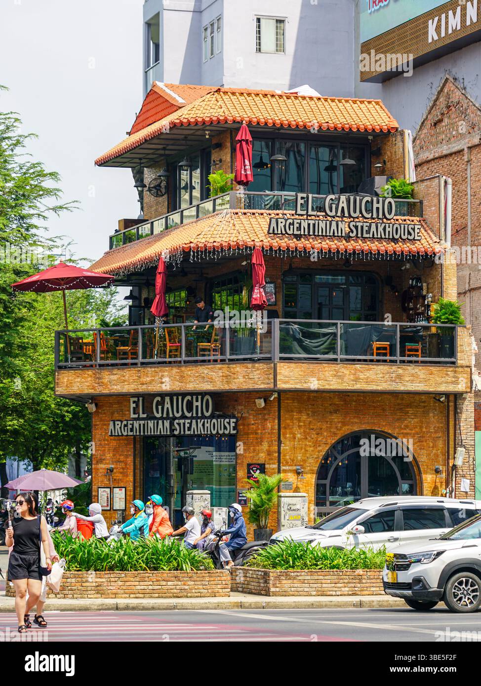 Ho Chi Minh-ville, Vietnam-16 mars 2025 : coin urbain animé avec El Gaucho Argentinian Steakhouse, motos, piétons et voitures dans le centre de Saigon Banque D'Images