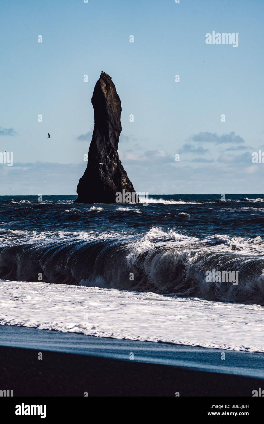 De puissantes vagues s'écrasent le long de la rive de Reynisfjara en Islande, avec une spectaculaire pile de basalte s'élevant de l'océan. Une vue emblématique de l'Islande Banque D'Images