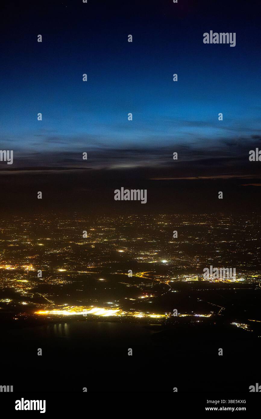 Vue aérienne époustouflante depuis un avion montrant une ville illuminée à la tombée de la nuit. Les lumières brillantes contrastent magnifiquement avec l'approfondissement du ciel, capturi Banque D'Images