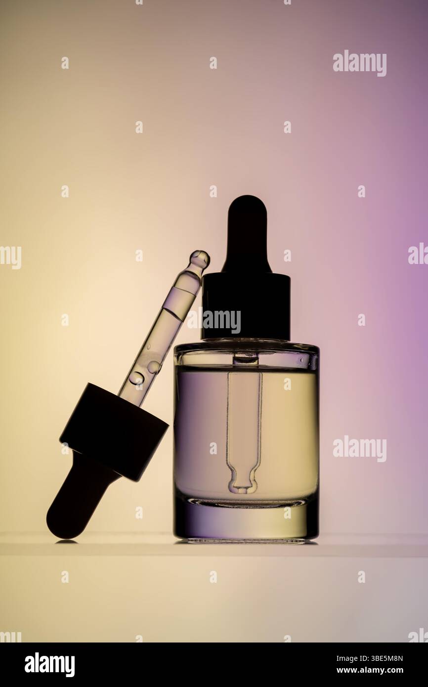 Une image élégante montrant un flacon de sérum pour le visage transparent avec un compte-gouttes, placé sur un fond dégradé rose et jaune doux. Idéal pour la beauté et skincar Banque D'Images