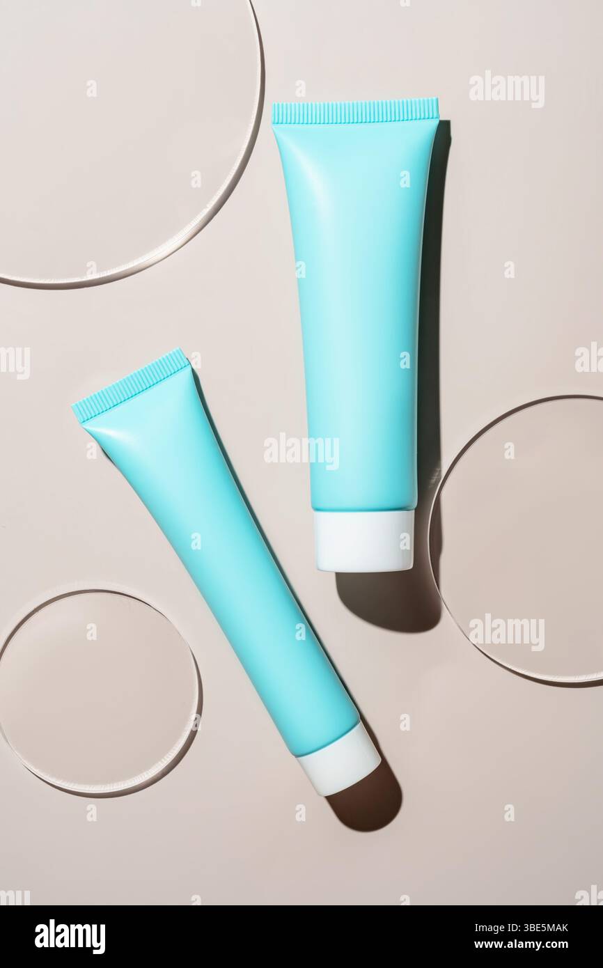 Tubes cosmétiques bleus astucieusement placés sur une surface lisse, avec des ombres douces et une surface circulaire. Le design minimaliste souligne l'élégance moderne Banque D'Images