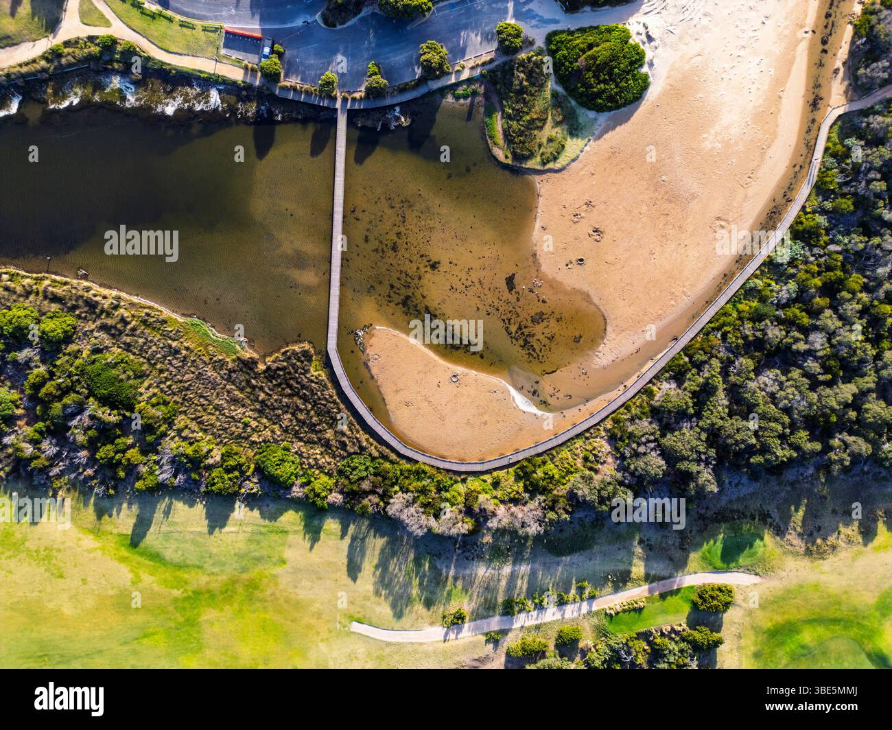 Vue aérienne d'un paysage côtier pittoresque avec une végétation verte, une voie d'eau sinueuse et une plage de sable, créant une scène naturelle tranquille dans Banque D'Images