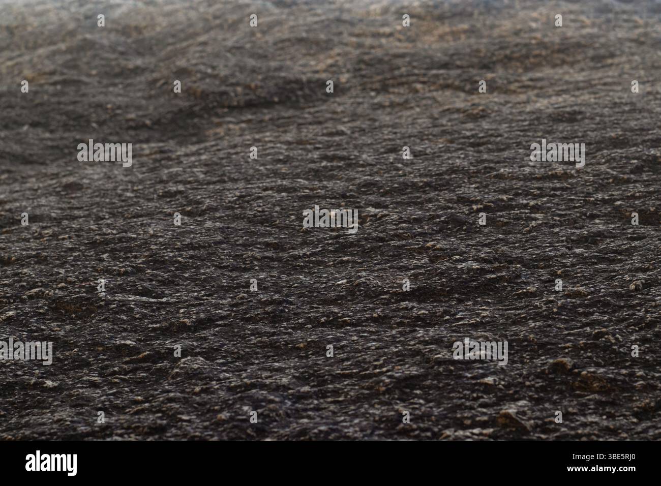 Gros plan sur un rocher avec texture sombre et lumière du soleil venant du haut Banque D'Images