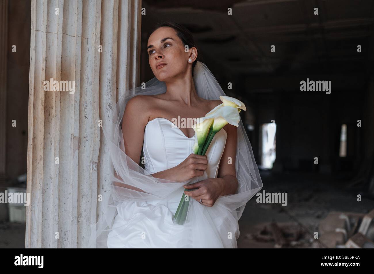 Une mariée dans une superbe robe blanche pose avec des lys calla dans une ancienne villa à Treia, en Italie. Le cadre élégant de la province de Macerata ajoute une touche intemporelle Banque D'Images