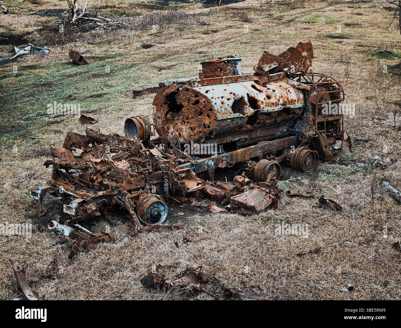 Vue de dessus d'un véhicule dévasté, détruit lors de la guerre en Ukraine. Les restes rouillés se trouvent dispersés sur un champ aride, mettant en valeur la sombre réalité de W. Banque D'Images