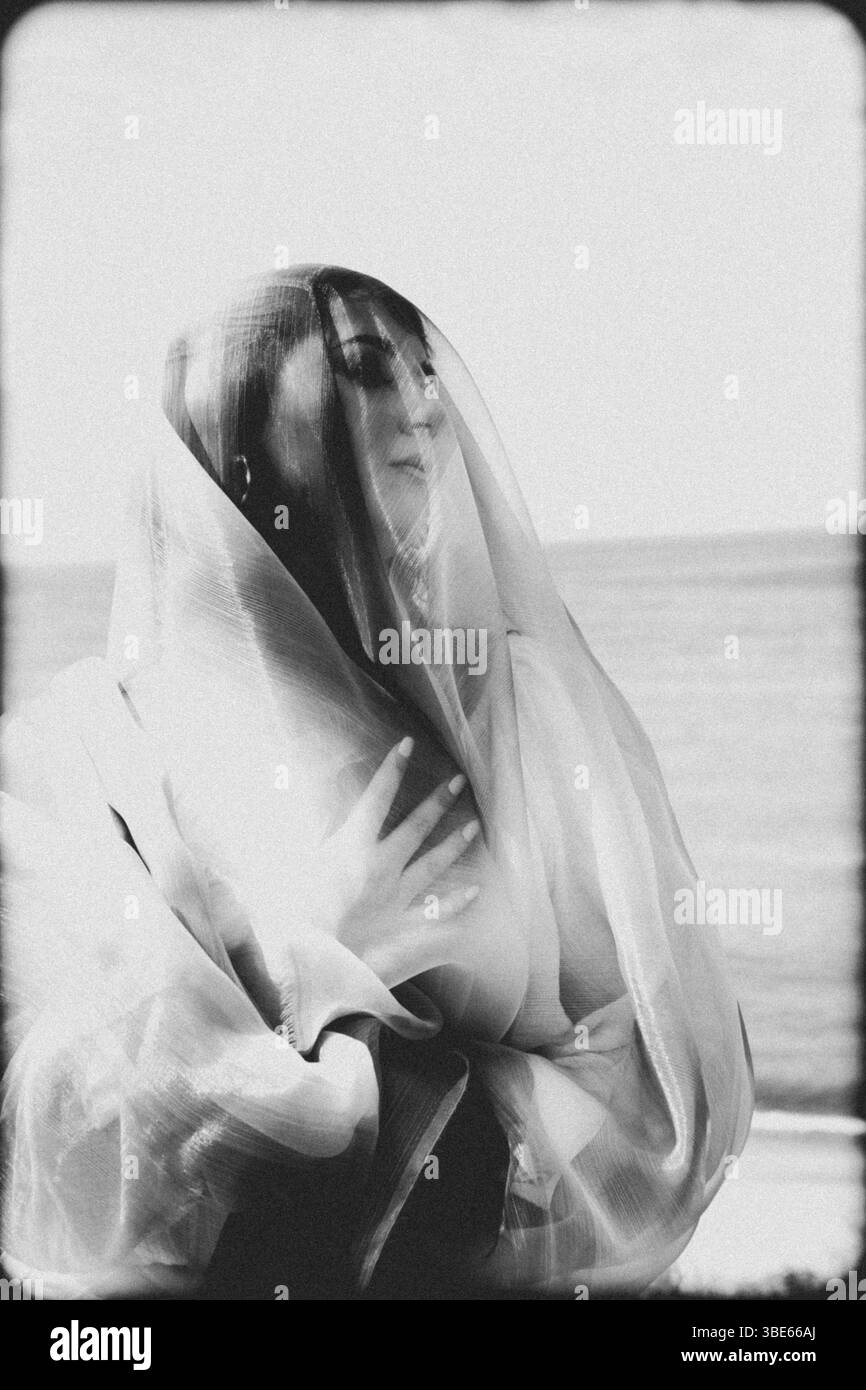 femme en vêtements blancs dansant avec un tissu bleu sur la plage Banque D'Images