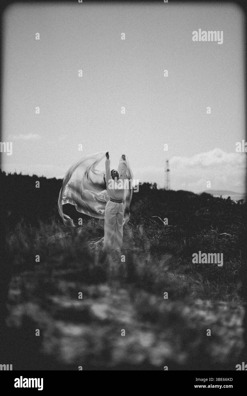 femme en vêtements blancs dansant avec un tissu bleu sur la plage Banque D'Images
