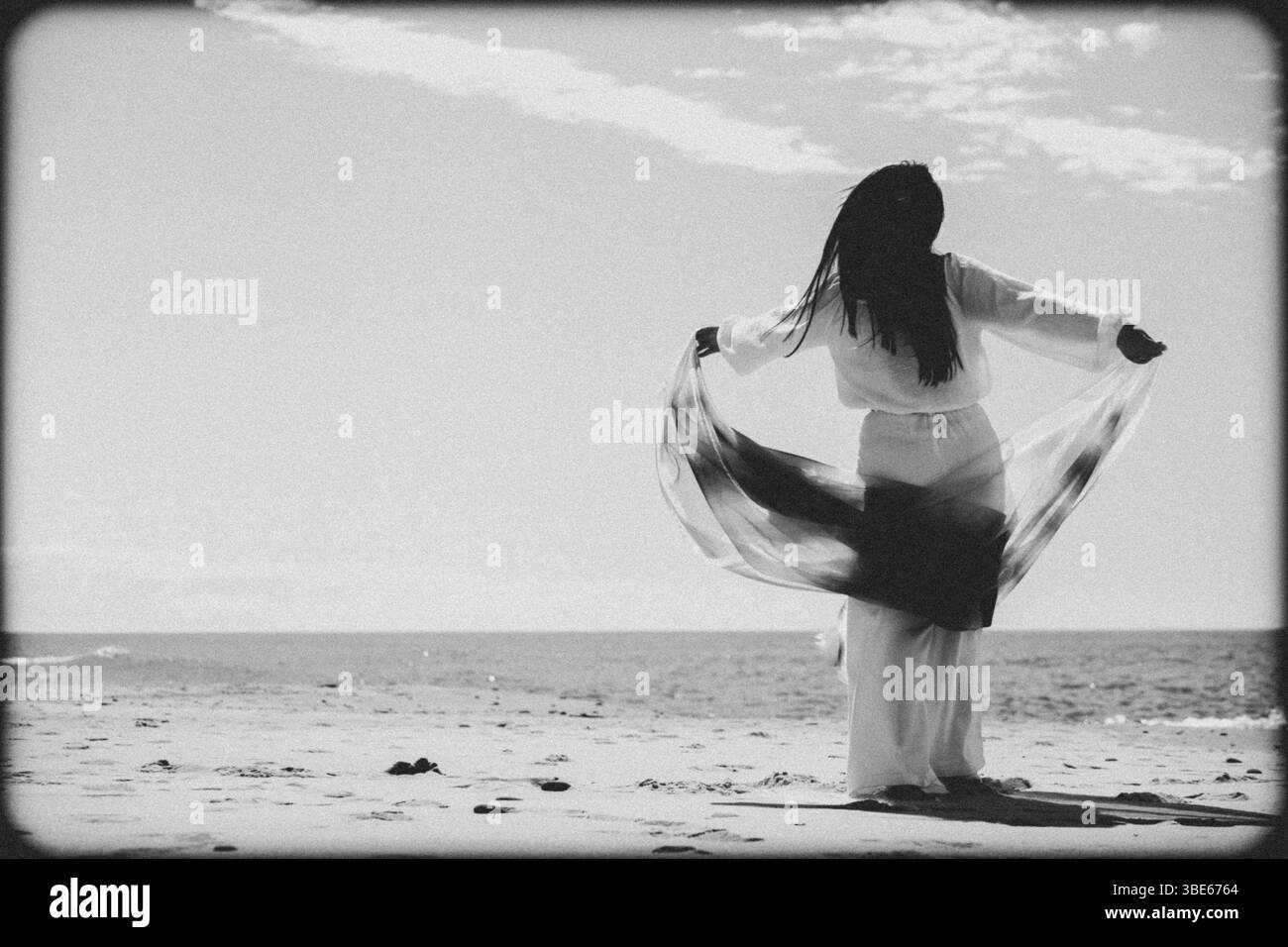 femme en vêtements blancs dansant avec un tissu bleu sur la plage Banque D'Images