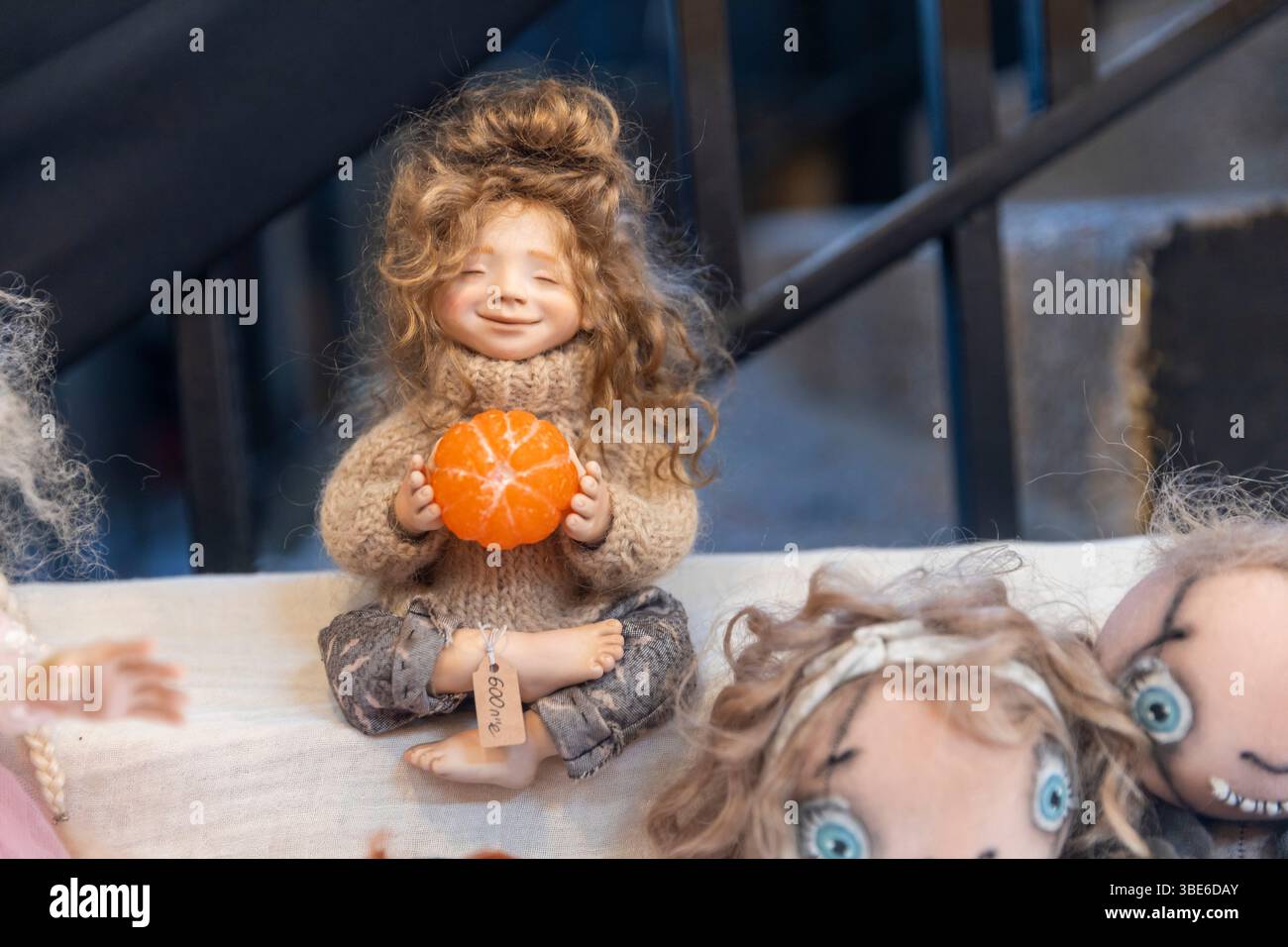 Haïfa, Israël – 24 mai 2025. Un gros plan d'une poupée textile faite à la main tenant un orange miniature sur l'affichage sur le marché Banque D'Images