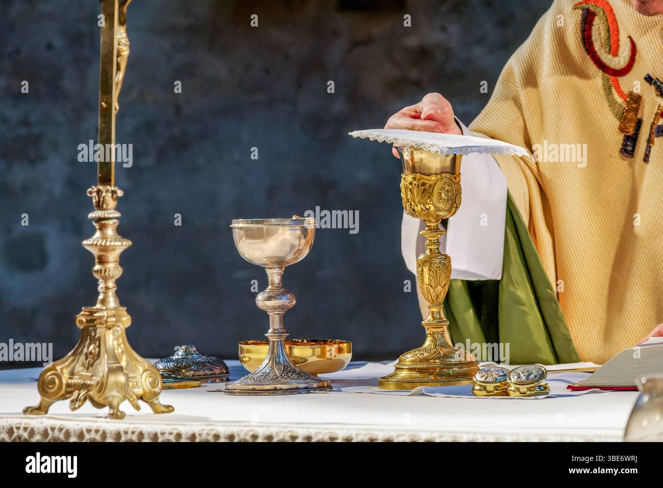 Un prêtre catholique élève le ciborium contenant les hôtes au-dessus de l'autel lors d'un Masséno solennel. Le missel ouvert se trouve dans le fond, soulignant le Banque D'Images