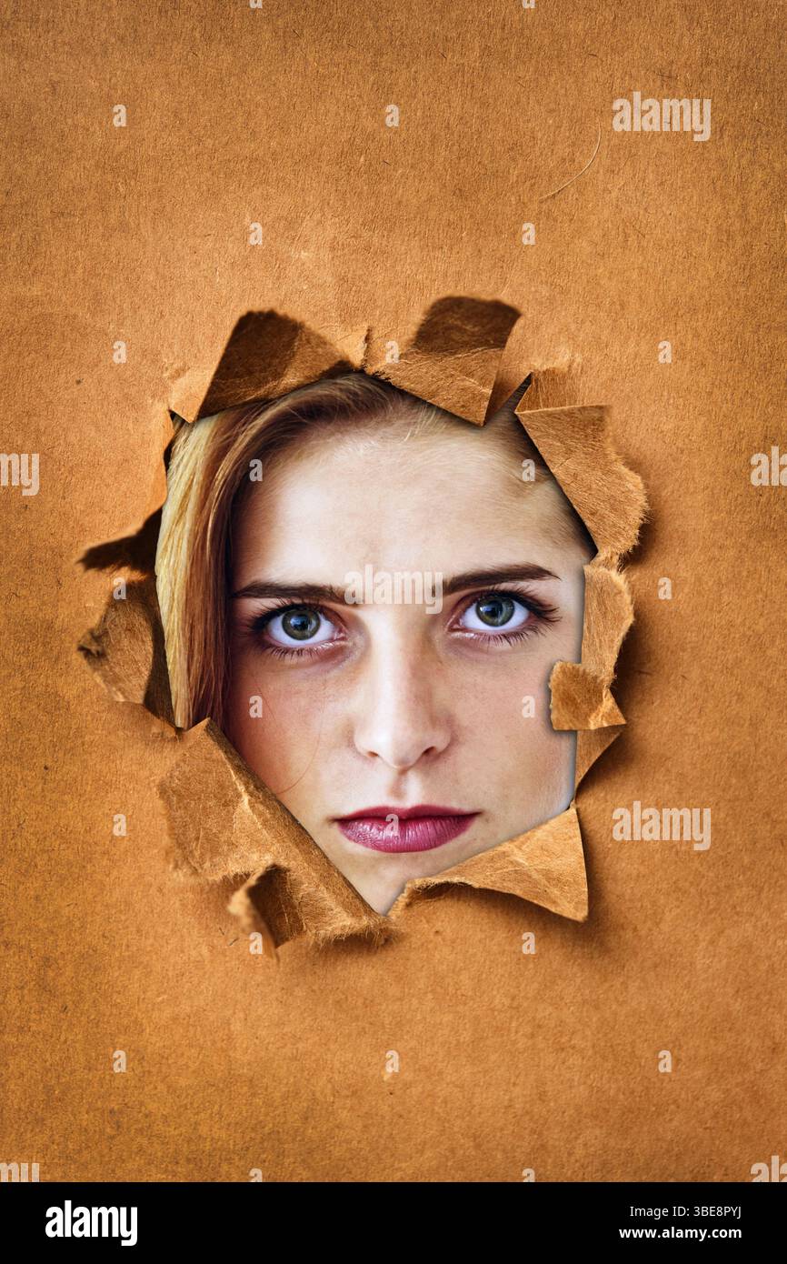 jeune femme face regardant de derrière un papier de ripper Banque D'Images