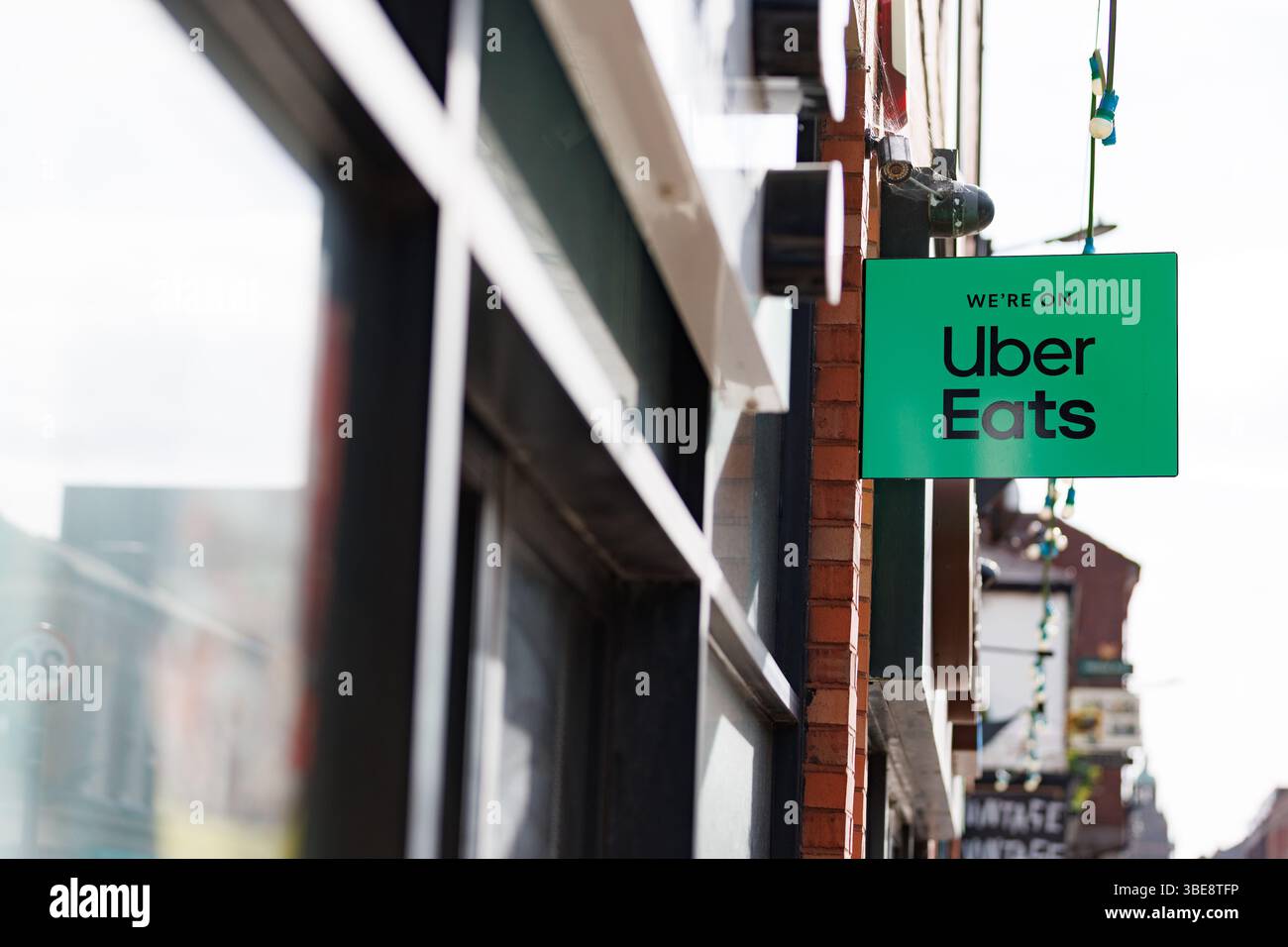 Un point de vente d'aliments annonçant qu'Uber mange via un panneau à l'extérieur du magasin. Logo vert Uber Eats avec la marque « We're on Uber Eats ». Uber Eats Royaume-Uni, Uber Eats Royaume-Uni, application de livraison Banque D'Images