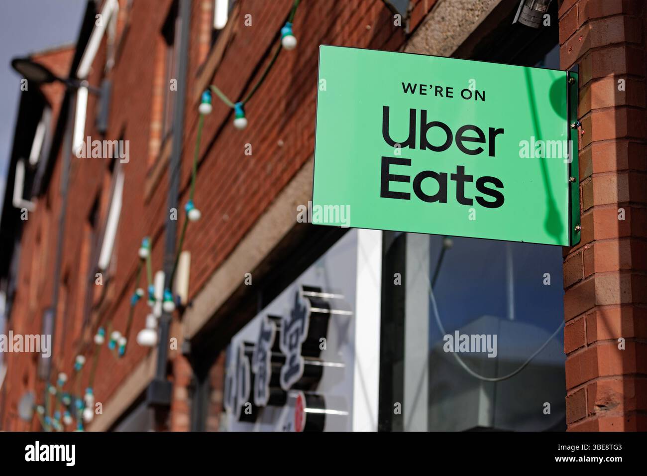 Un point de vente d'aliments annonçant qu'Uber mange via un panneau à l'extérieur du magasin. Logo vert Uber Eats avec la marque « We're on Uber Eats ». Uber Eats Royaume-Uni, Uber Eats Royaume-Uni, application de livraison Banque D'Images
