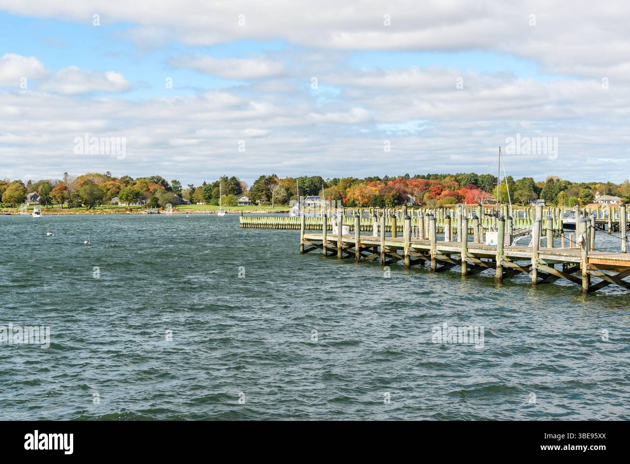 Jetées wwoden vides dans le port un jour d'automne partiellement nuageux. Les bateaux ancrés sont visibles en arrière-plan. Banque D'Images