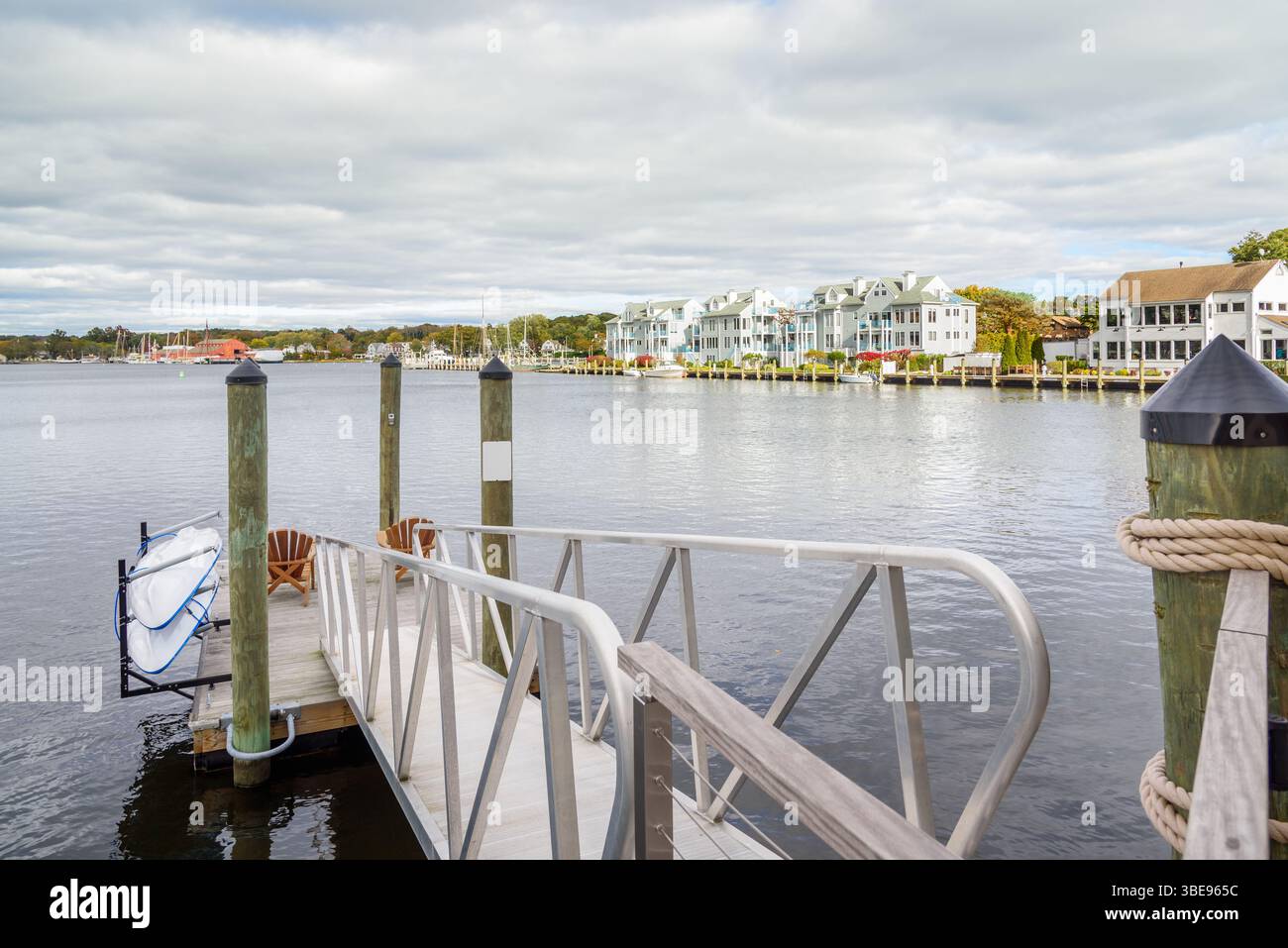 Fauteuils en bois vides sur une jetée flottante sur une rivière par un jour nuageux d'automne Banque D'Images