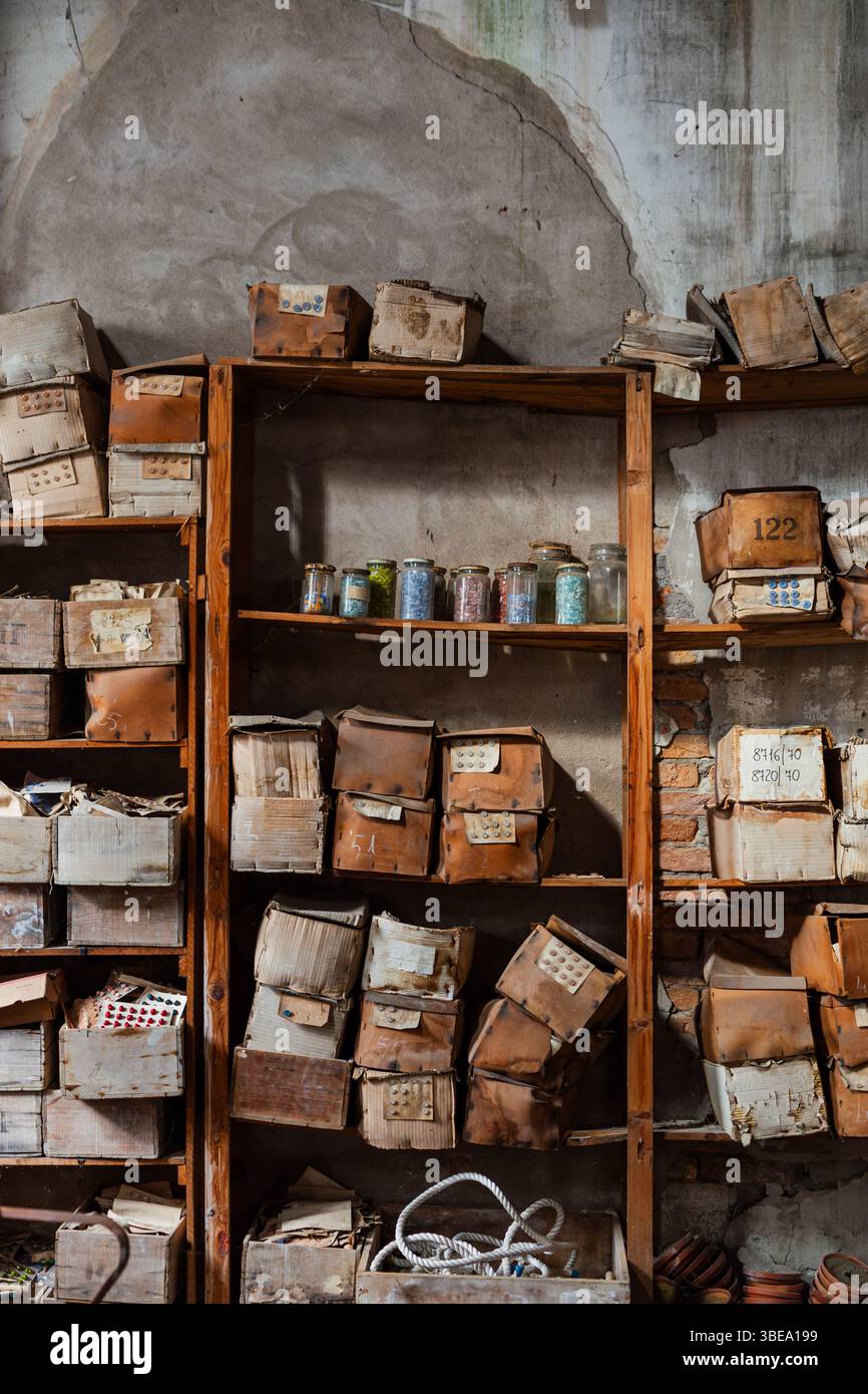 Les étagères en bois vieilli et robustes sont chargées de boîtes et de conteneurs poussiéreux, certains ouverts avec de vieux documents ou objets, Banque D'Images