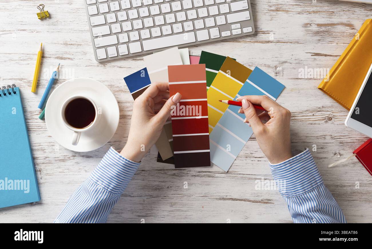 Concepteur Web choisissant des couleurs à partir de nuances au bureau en bois. Lieu de travail de bureau avec clavier d'ordinateur et tasse de café. Conception de l'interface utilisateur de mobi Banque D'Images