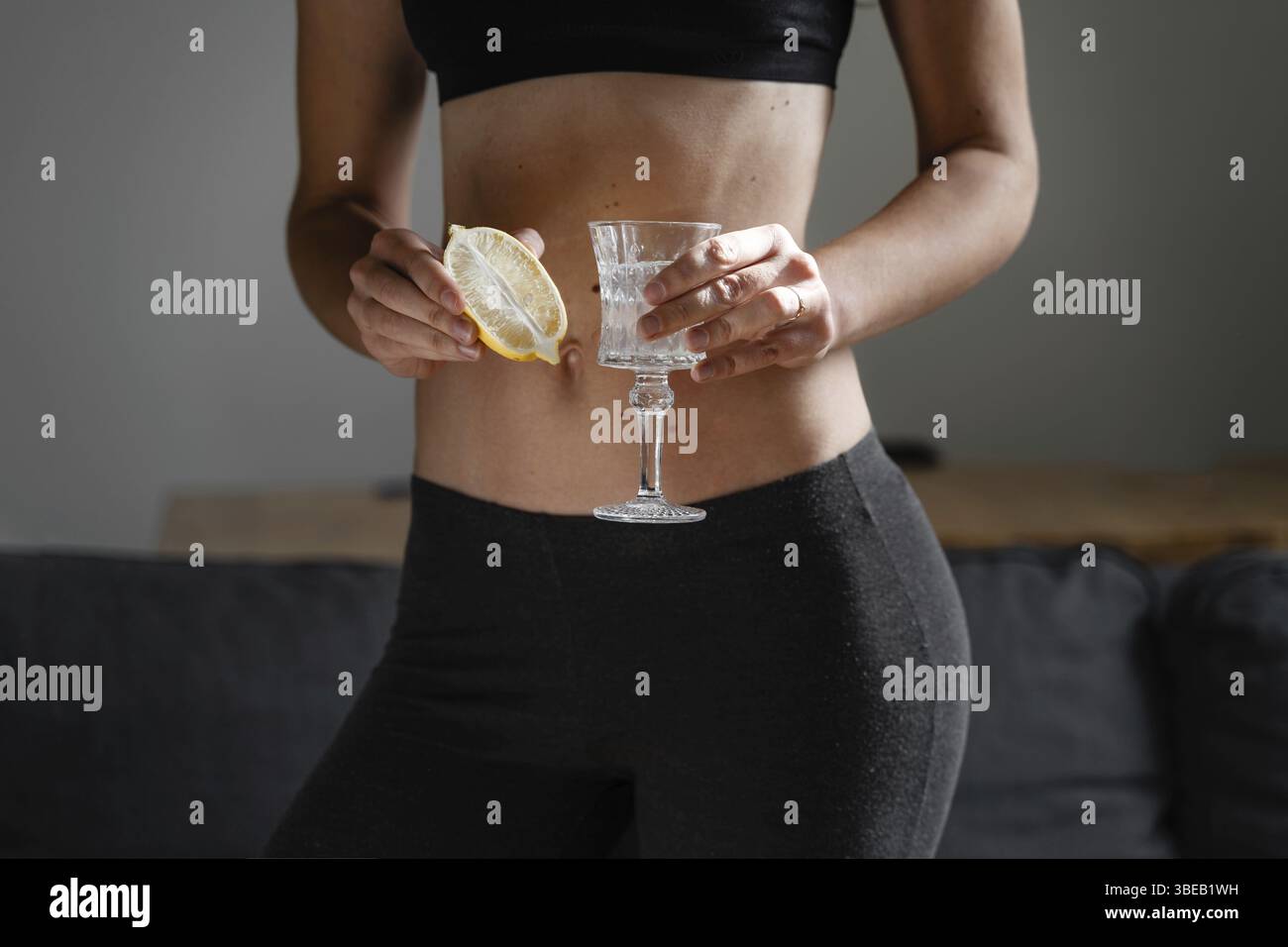 Gros plan de jeune femme mince en forme de préparation de l'eau avec du jus de citron. Rituel du matin. Antioxydant sain. Régime amincissant. Stimuler l'immunité et le métabolisme . Banque D'Images