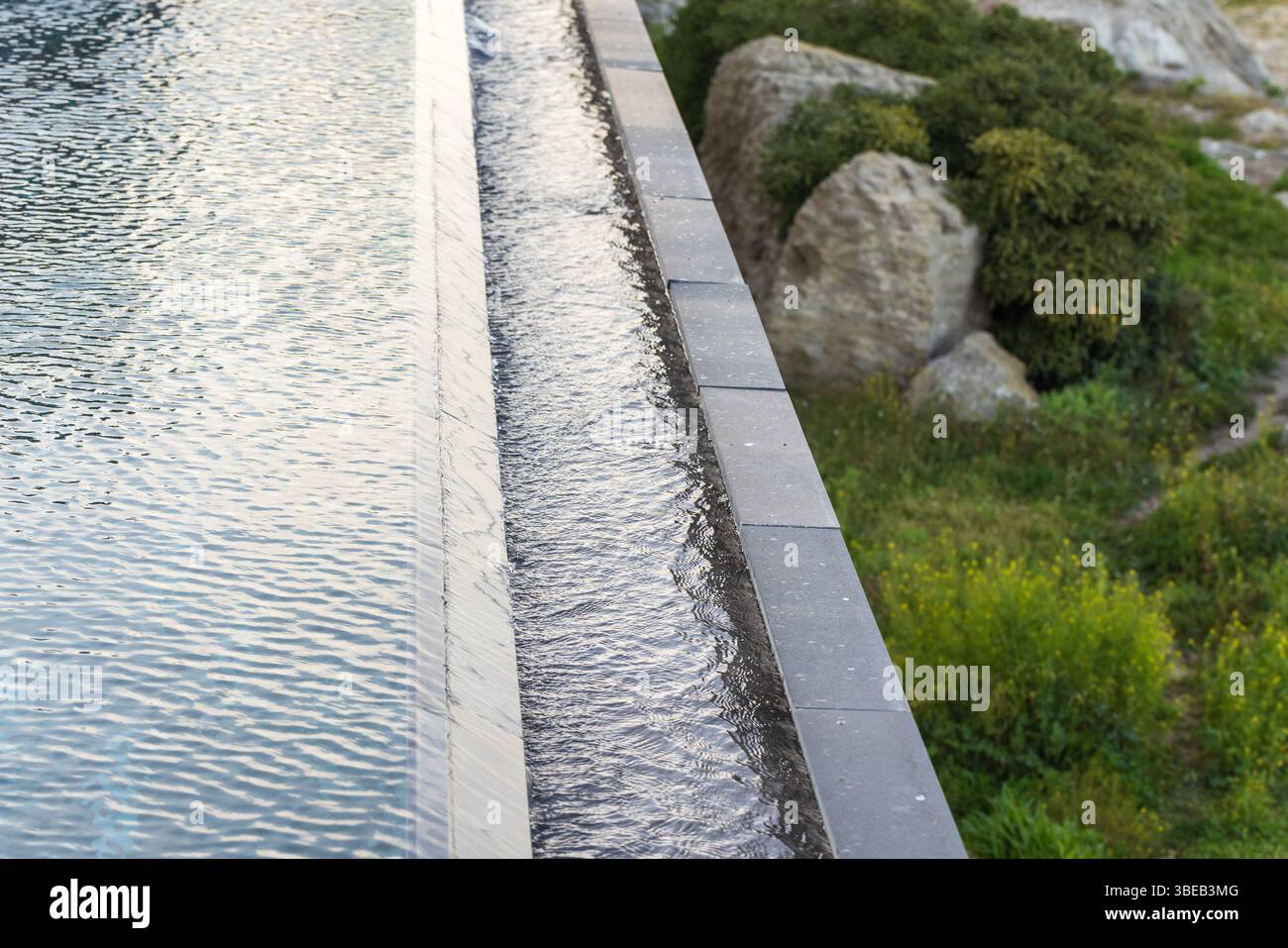 Une eau sereine avec de l'eau débordante à côté des rochers, mêlant nature et calme et design moderne Banque D'Images