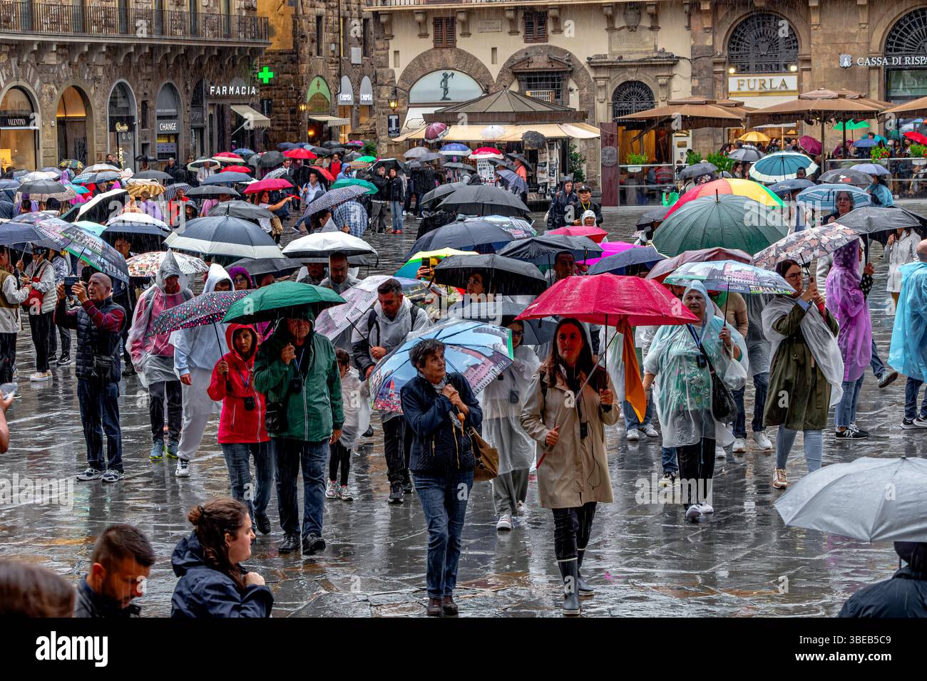 Foules de personnes qui s'abritent sous des parapluies sous de fortes pluies sur la Piazza della Signoria à Florence, Italie Banque D'Images