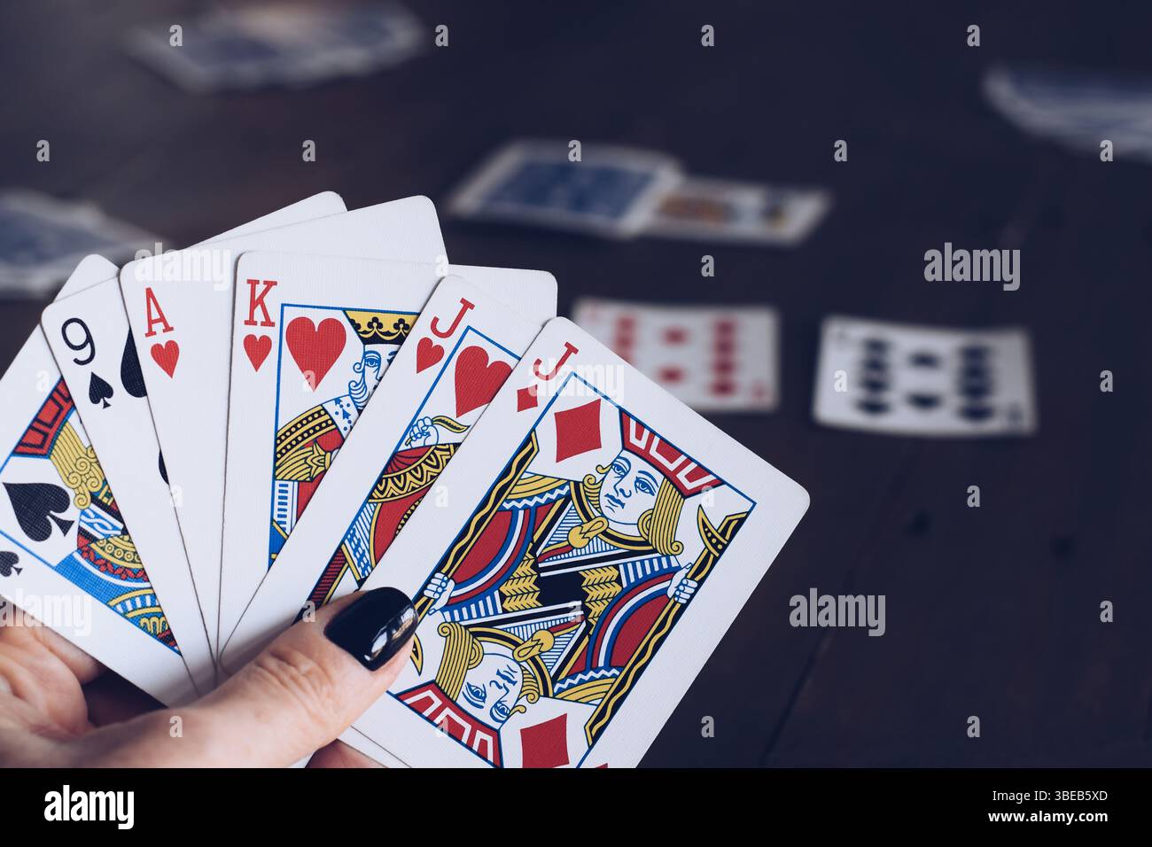 Main pour femmes tenant des cartes à jouer à une table Banque D'Images