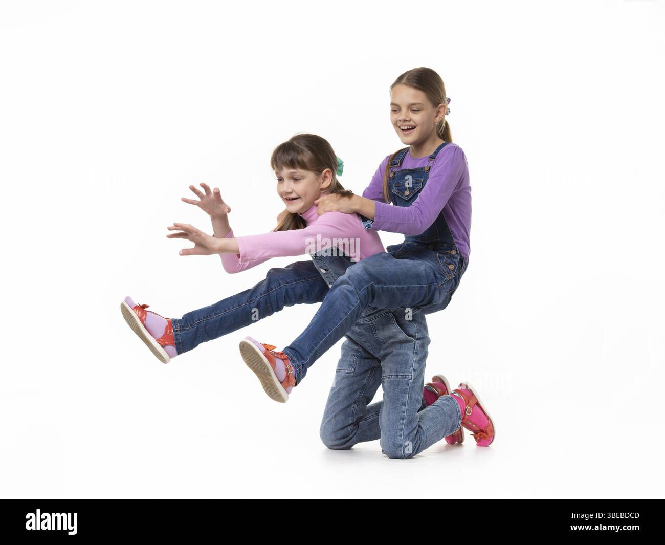 Une fille hilarante se promette sur elle-même, en surmontant sa sœur sur fond blanc Banque D'Images