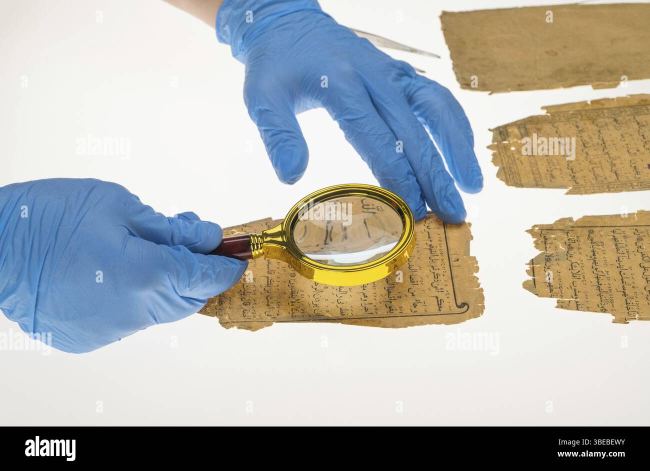 Un chercheur étudie l'écriture arabe du Coran à l'aide d'une loupe et d'une table avec une lumière. Paléographie, l'étude de l'écriture arabe ancienne Banque D'Images