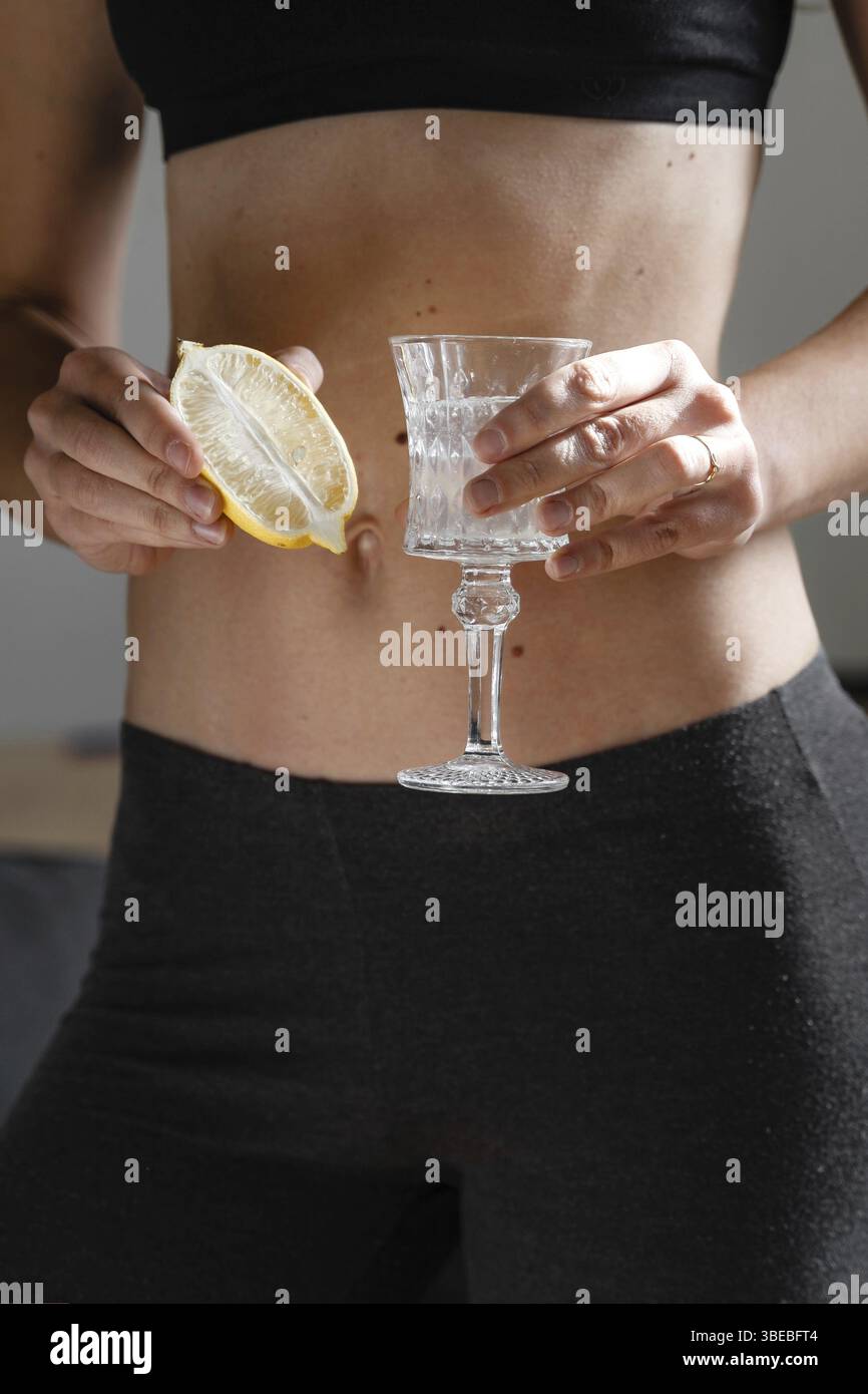 Gros plan de jeune femme mince en forme de préparation de l'eau avec du jus de citron. Rituel du matin. Antioxydant sain. Régime amincissant. Stimuler l'immunité et le métabolisme . Banque D'Images