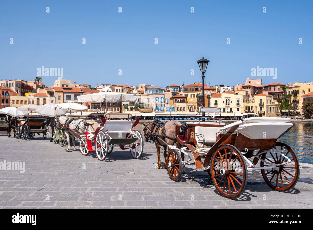 Chania Crète. Calèches dans une rangée au vieux port vénitien, bâtiments traditionnels en bord de mer et ciel bleu Banque D'Images