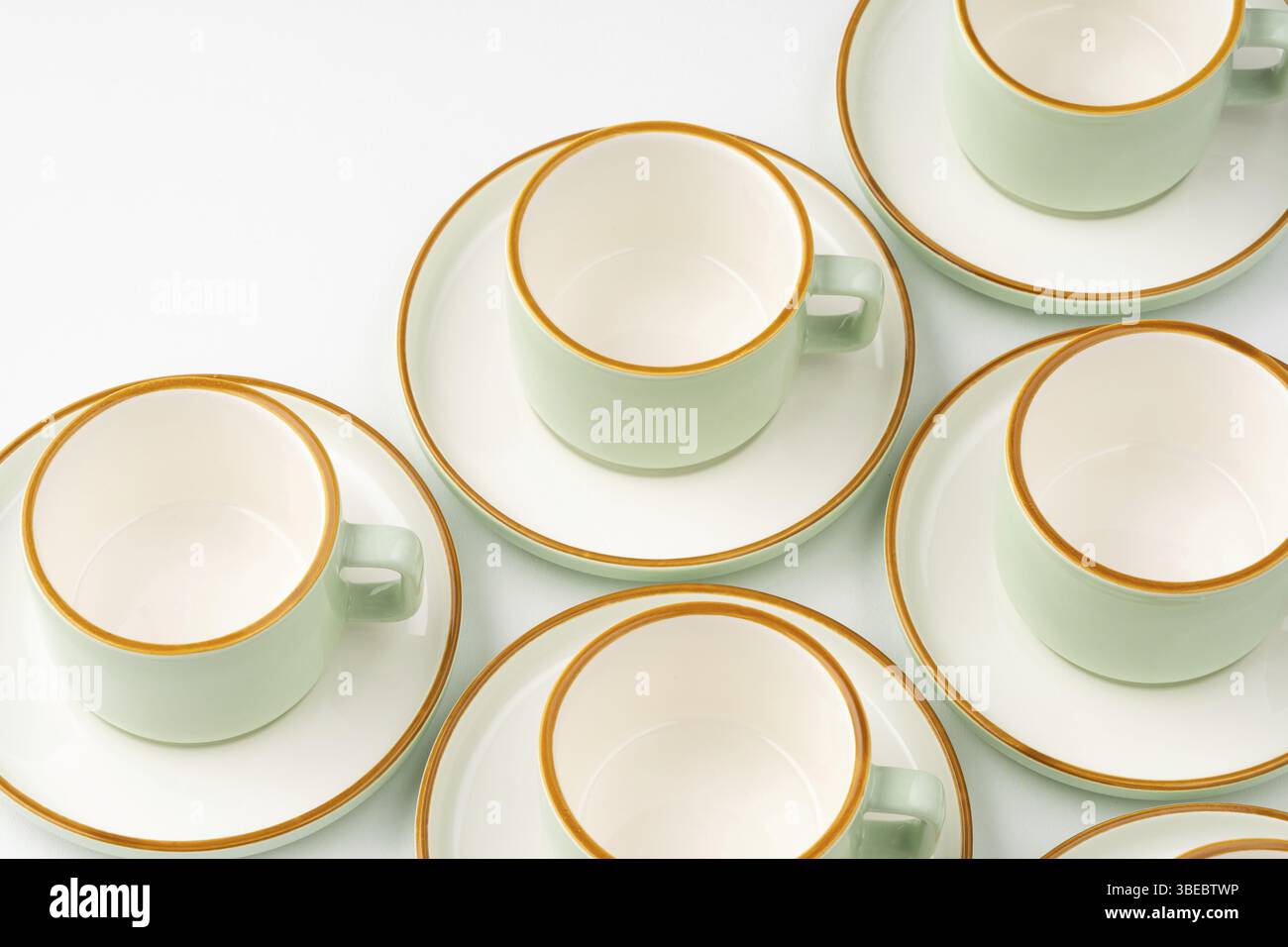Un ensemble de tasses en céramique blanc et vert pastel aux contours orange Banque D'Images