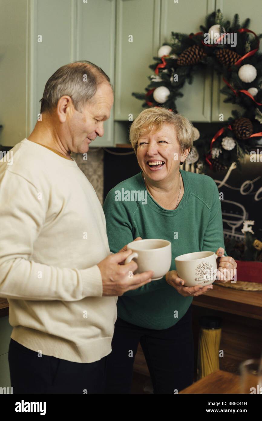 Photo de couple âgé des années 60 profitant de la vie à la cuisine avec des tasses de café. saint valentin des vieux couples amoureux. arrêtez la discrimination fondée sur l'âgisme. Banque D'Images