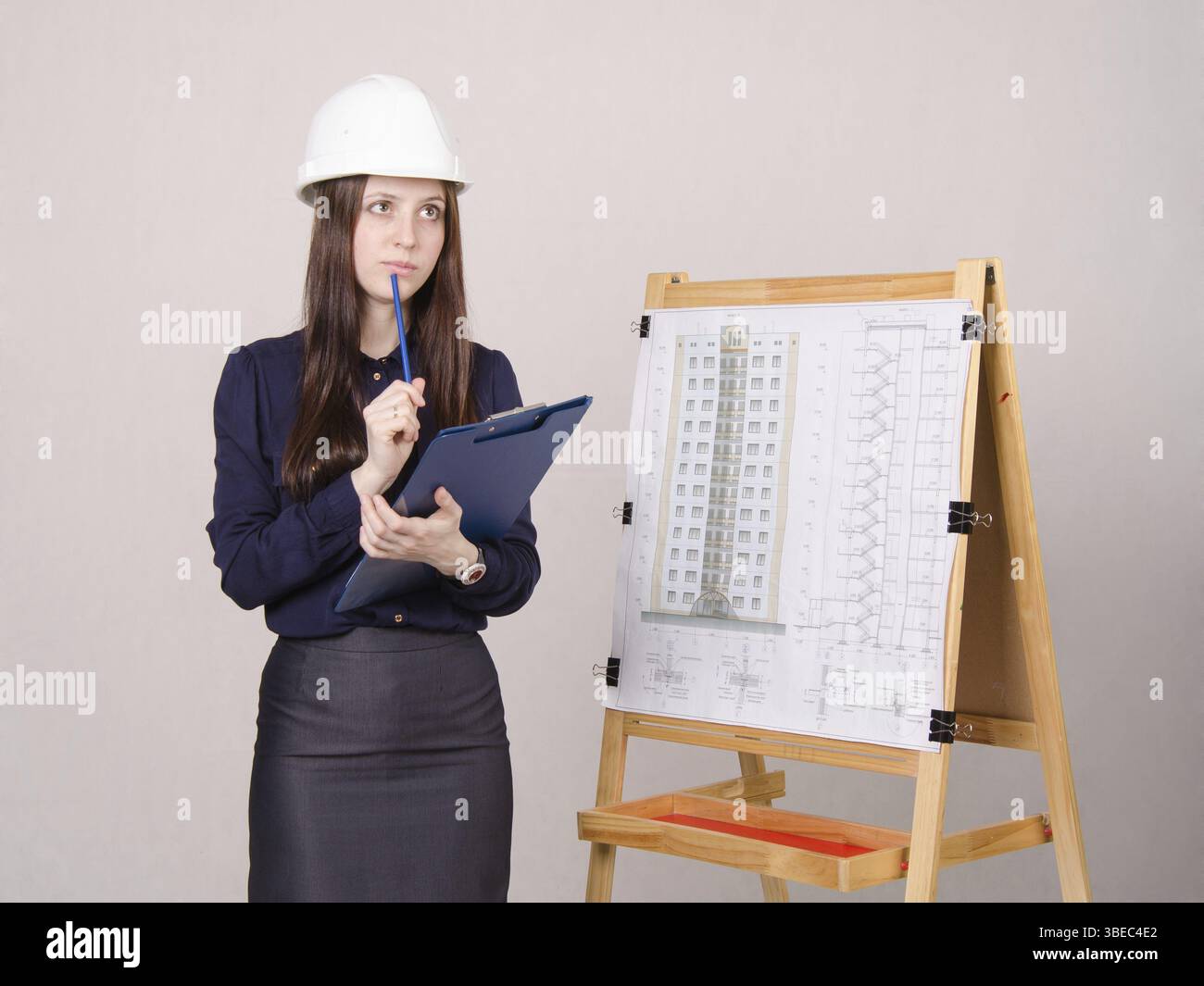 Jeune femme debout à l'architecte conseil de dessin monté sur le projet d'un immeuble de plusieurs étages Banque D'Images