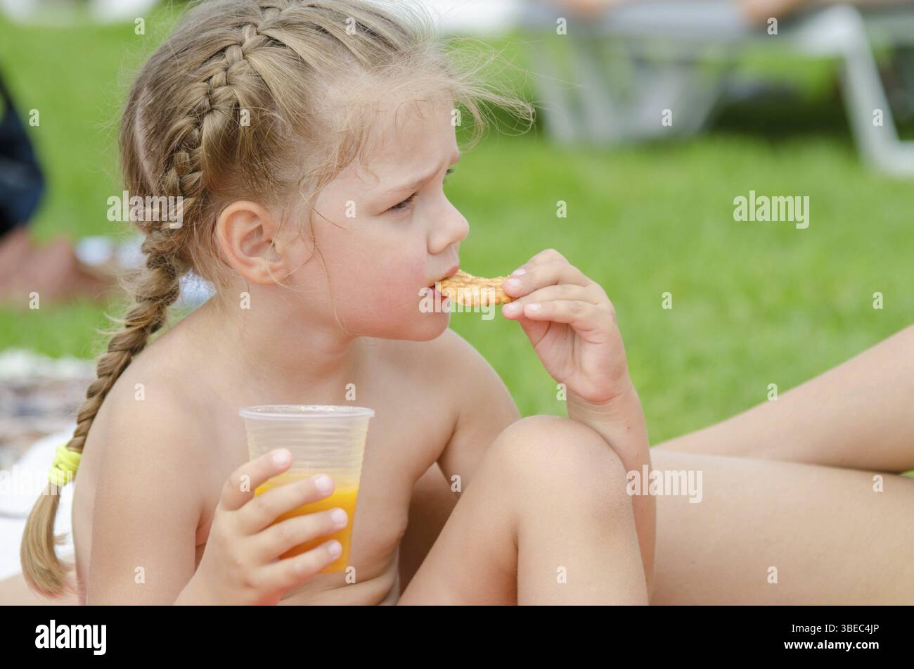 Girl eating cookies et boire du jus d'un gobelet jetable en plastique Banque D'Images