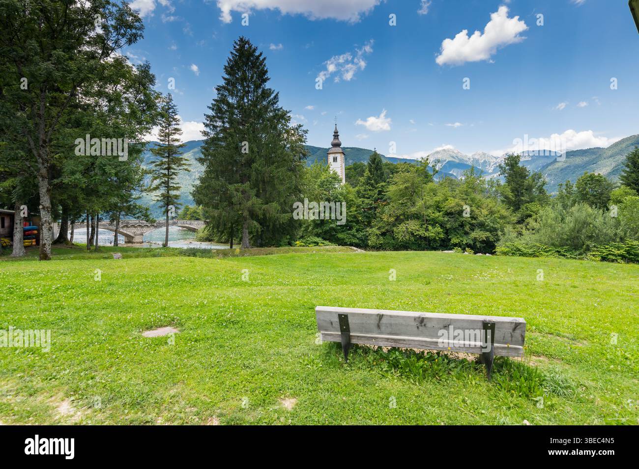 Église de Bohinj dans le village de Ribcev Laz, Slovénie. Vue sur la vieille église ancienne depuis le parc avec banc. alpes slovènes avec Triglav en arrière-plan, gras Banque D'Images