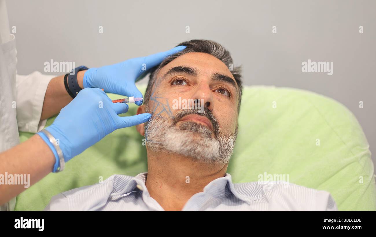 Médecin administrant une injection cosmétique au visage d'un patient masculin médecin administrant une injection cosmétique au visage d'un patient masculin, marqué pour le Banque D'Images