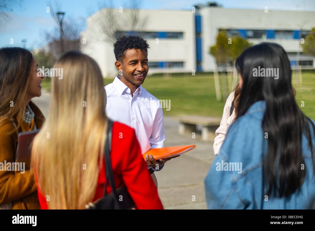 Groupe d'étudiants universitaires multiethniques joyeux discutant ensemble sur le campus pendant une pause entre les classes Banque D'Images