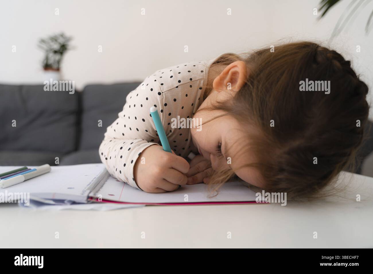 Portrait de fille enfant mignonne d'âge préscolaire dessinant avec des crayons à la maison tout en étant assis devant la caméra avec le visage attentif. Photo de stock. Banque D'Images