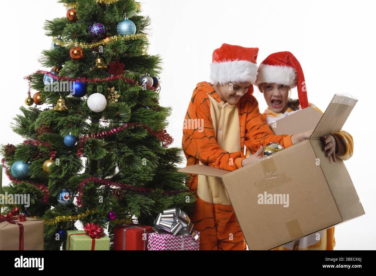 La fille drôle tient une boîte avec les jouets du nouvel an, une autre fille plonge dans une boîte Banque D'Images